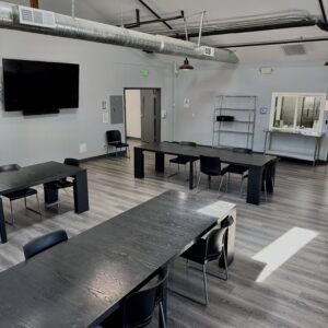 A modern, well-lit community meeting room with tables and chairs for events.